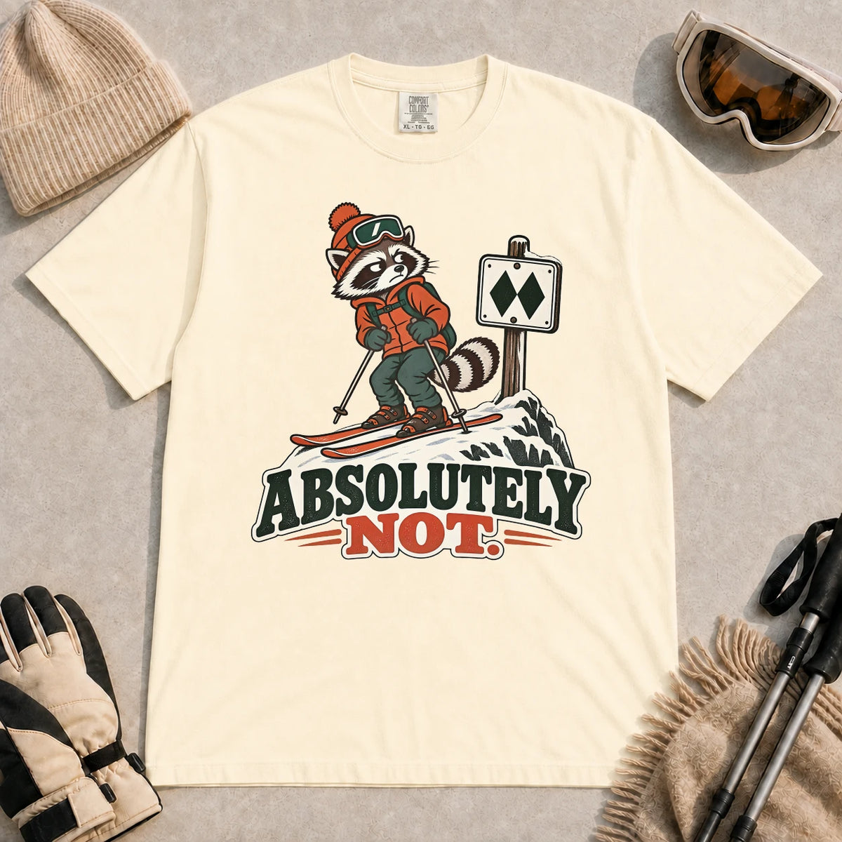 Ivory tee featuring a wary raccoon skier beside a double black diamond trail sign above the phrase “Absolutely Not.”