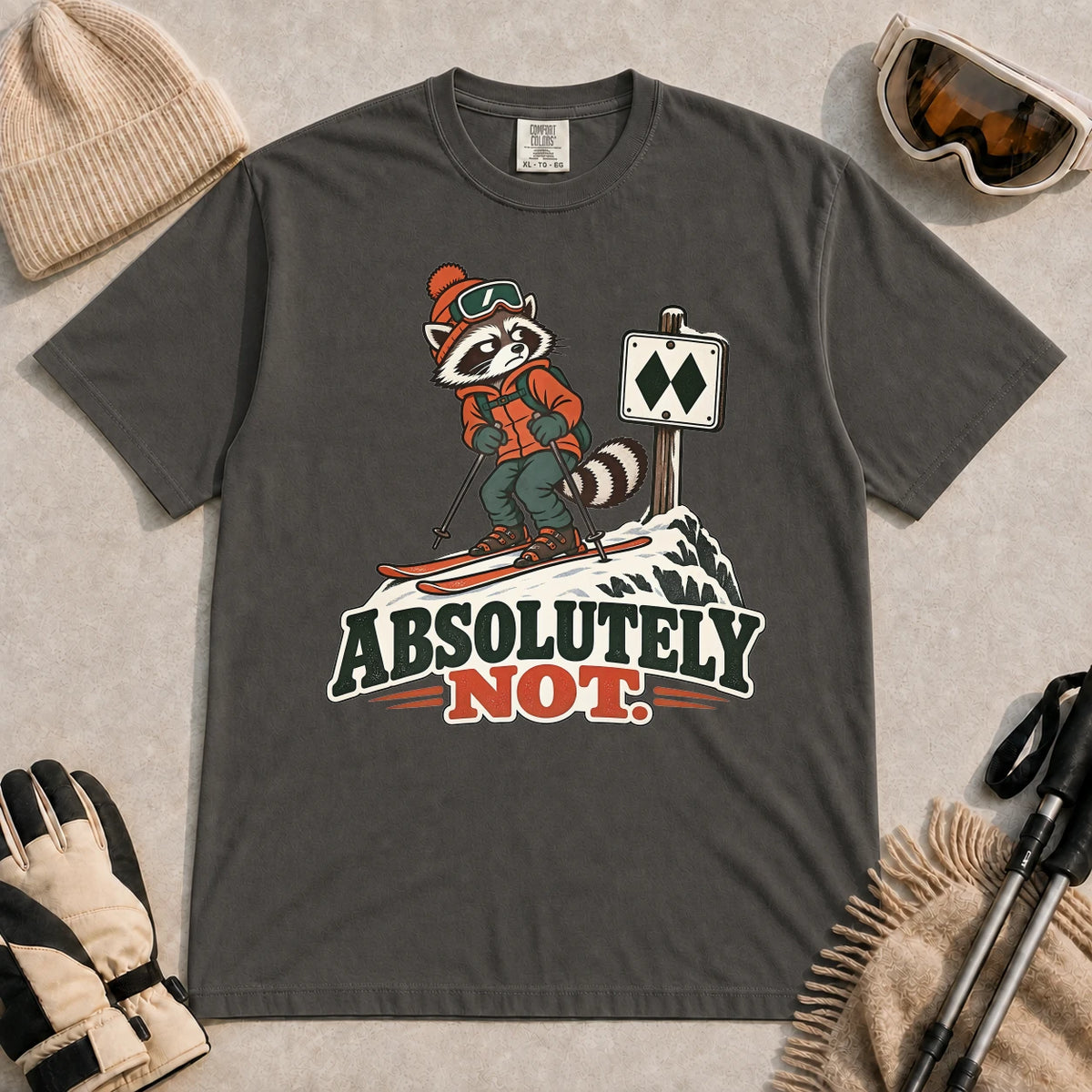 Pepper tee featuring a wary raccoon skier beside a double black diamond trail sign above the phrase “Absolutely Not.”