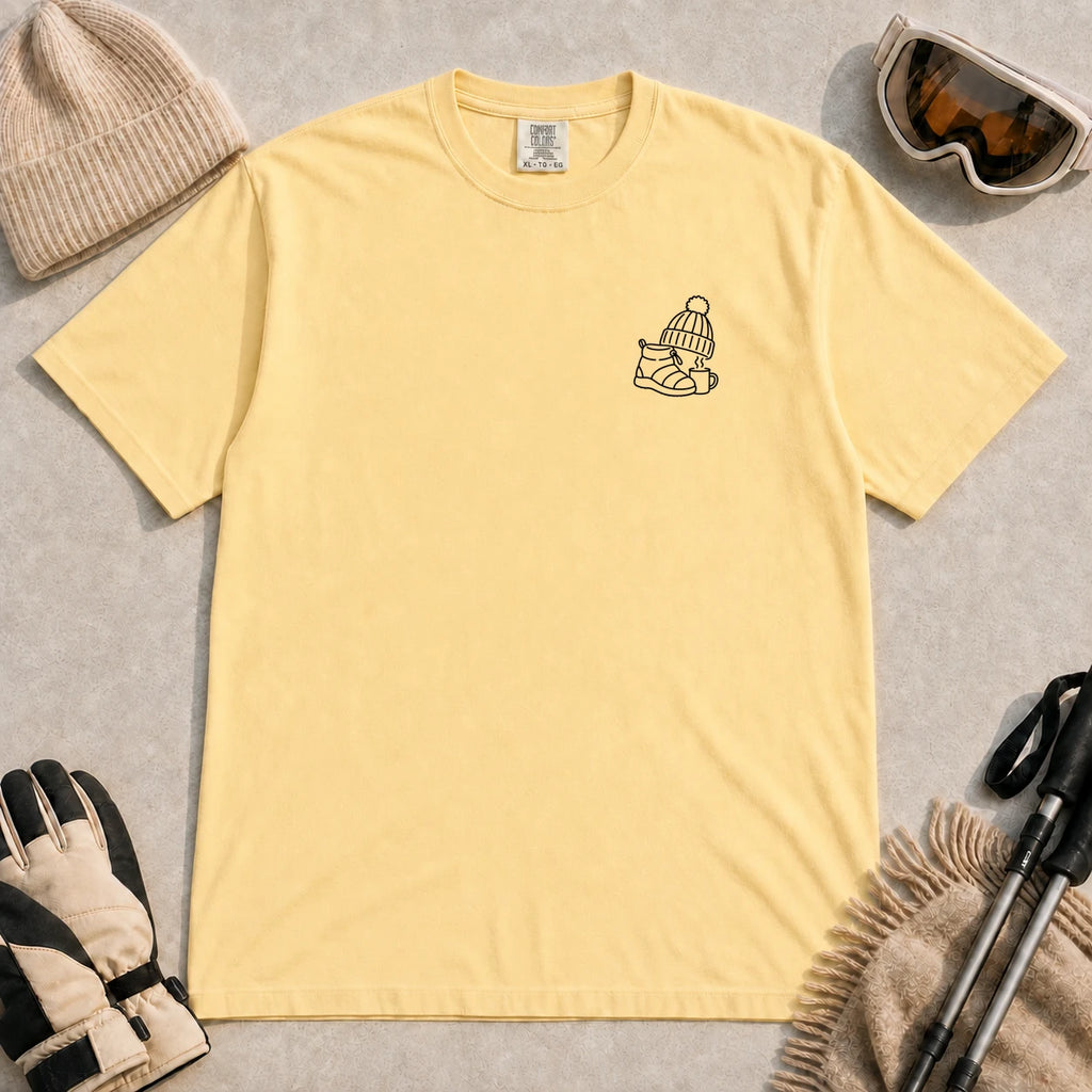 Butter tee featuring a minimalist black line-art design of a ski boot, winter beanie, and steaming mug on the left chest.