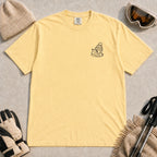 Butter tee featuring a minimalist black line-art design of a ski boot, winter beanie, and steaming mug on the left chest.