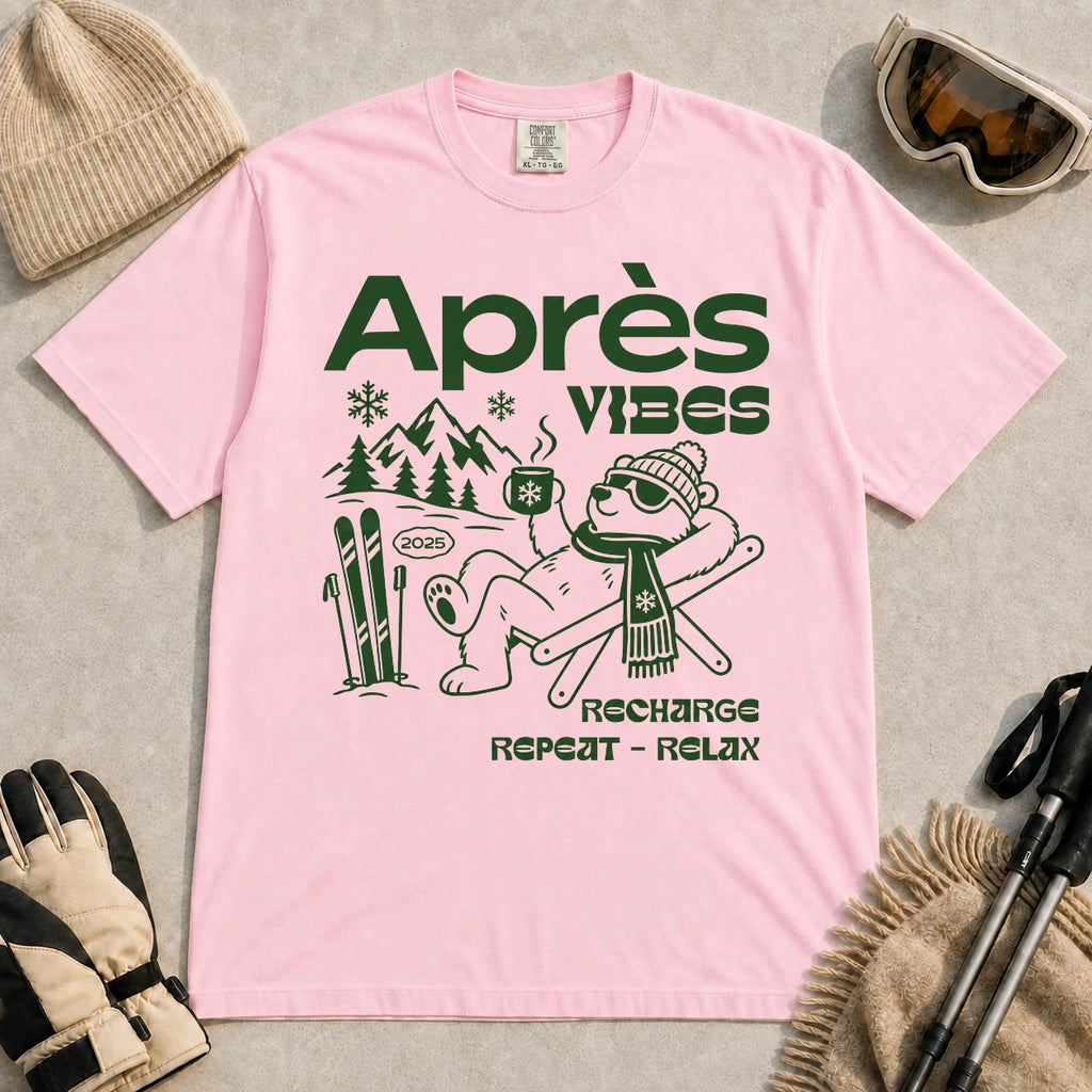 Blossom tee featuring a relaxed bear in sunglasses holding a steaming mug beside skis, with retro green “Après Vibes” and “Recharge, Repeat – Relax” text.