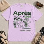 Orchid tee featuring a relaxed bear in sunglasses holding a steaming mug beside skis, with retro green “Après Vibes” and “Recharge, Repeat – Relax” text.