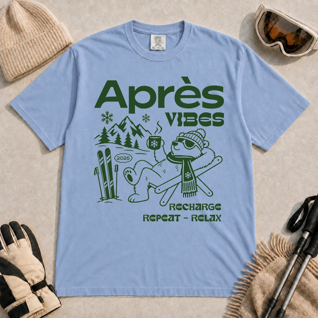 Washed Denim tee featuring a relaxed bear in sunglasses holding a steaming mug beside skis, with retro green “Après Vibes” and “Recharge, Repeat – Relax” text.