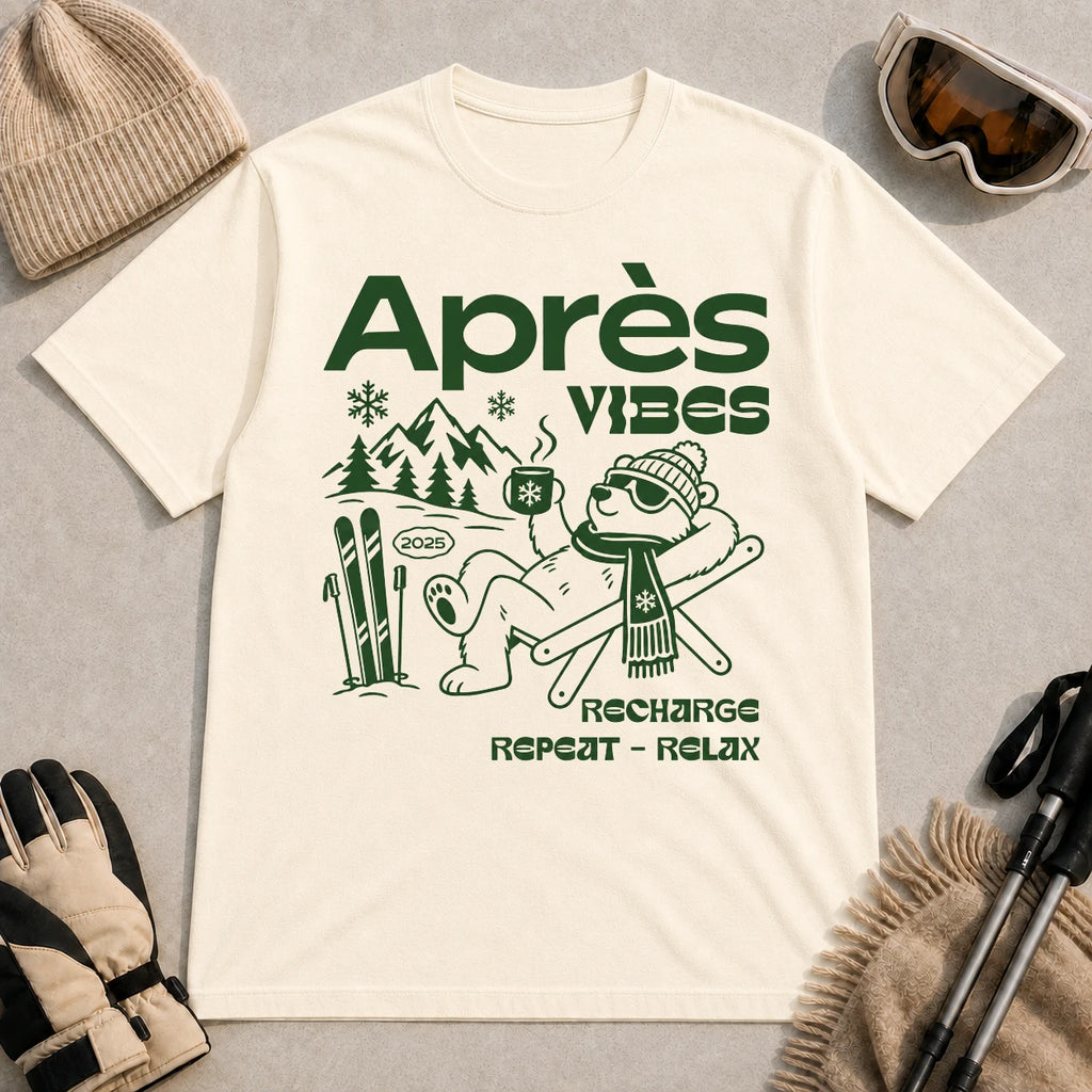 Natural tee featuring a relaxed bear in sunglasses holding a steaming mug beside skis, with retro green “Après Vibes” and “Recharge, Repeat – Relax” text.