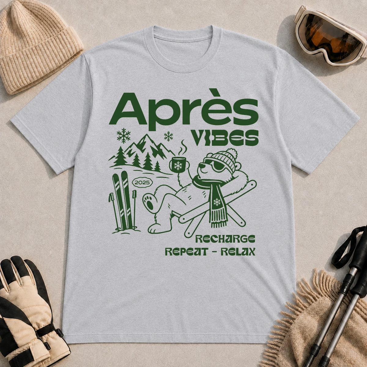 Sport Grey tee featuring a relaxed bear in sunglasses holding a steaming mug beside skis, with retro green “Après Vibes” and “Recharge, Repeat – Relax” text.