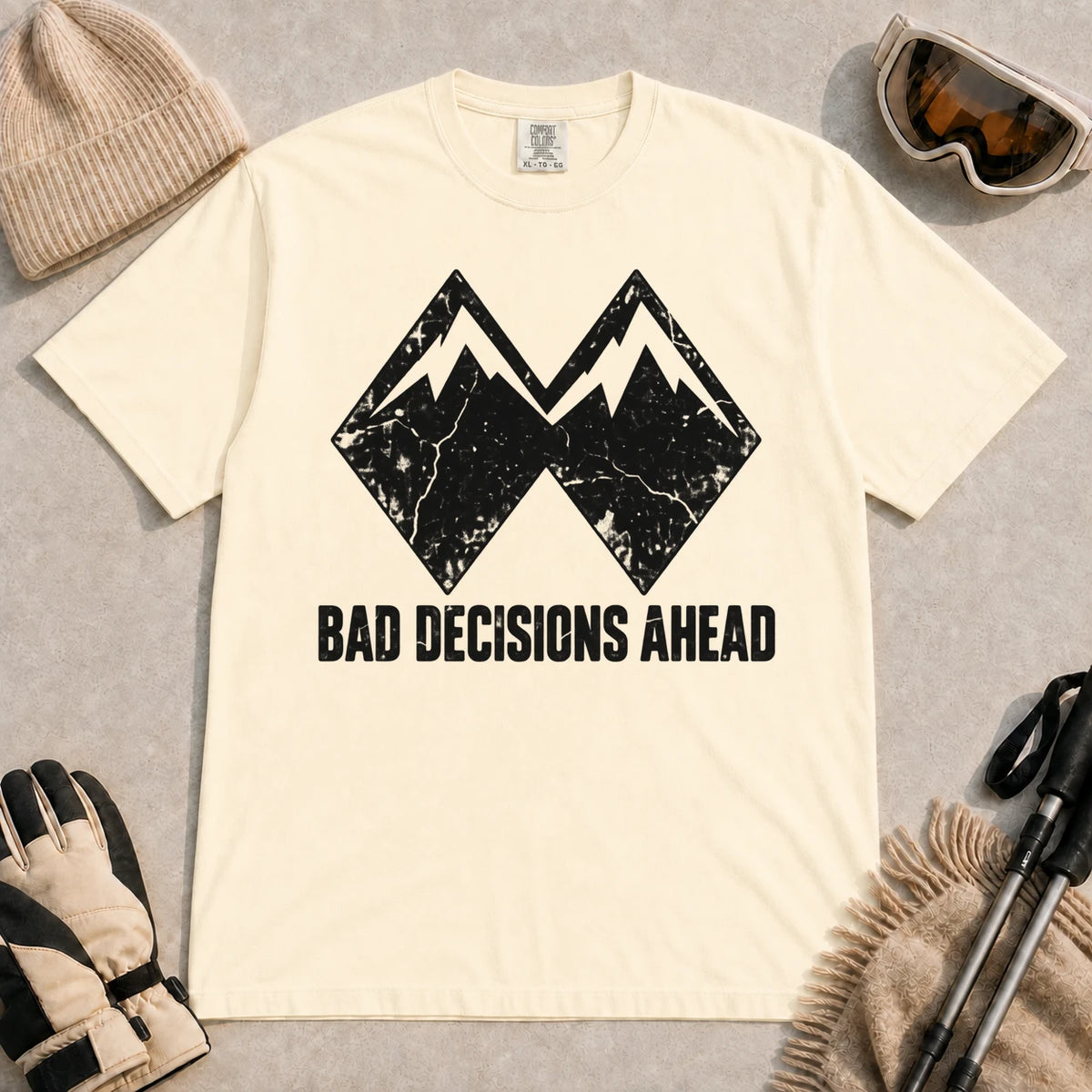 Ivory tee featuring a distressed black double-mountain graphic above the phrase “Bad Decisions Ahead.”