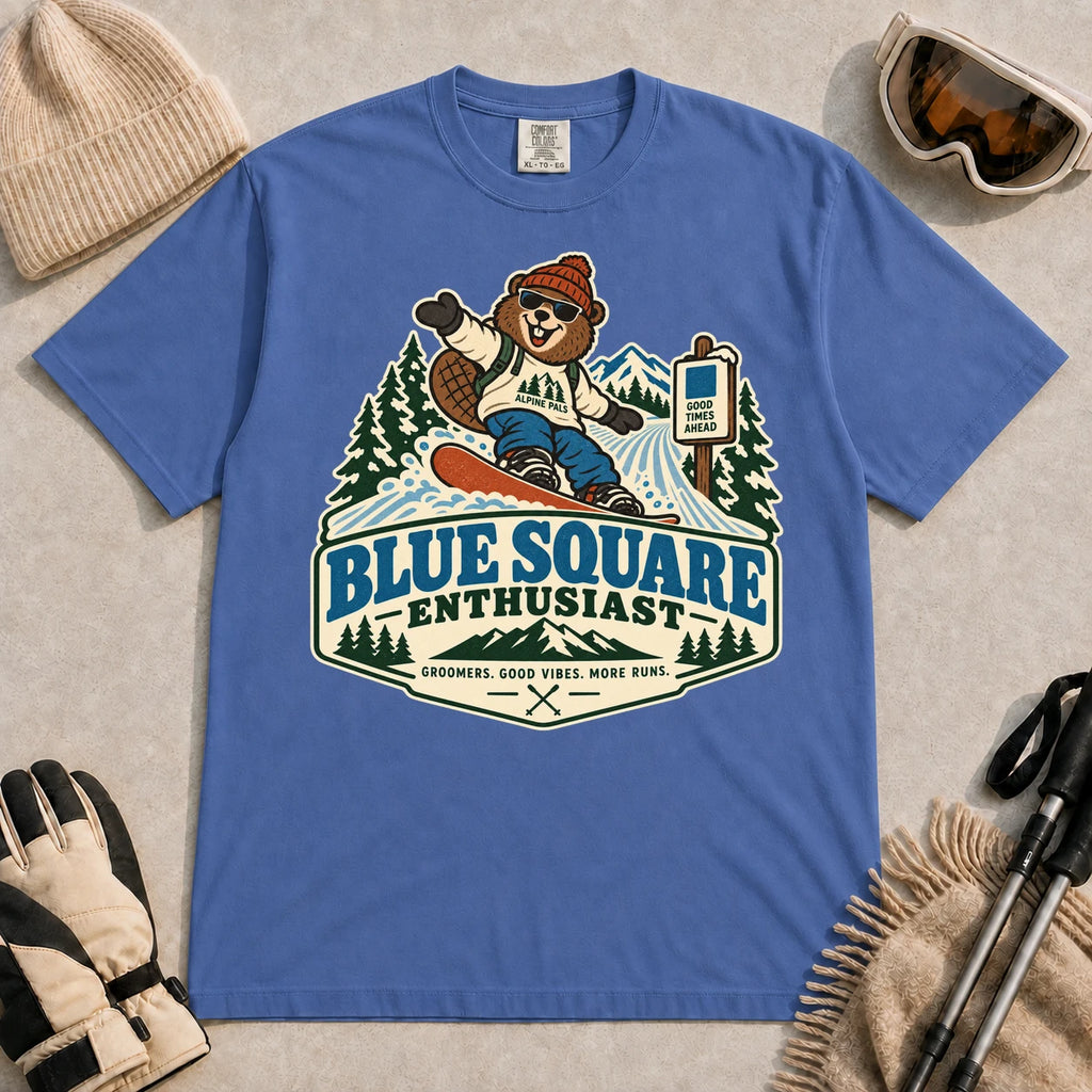 Mystic Blue tee featuring a cheerful bear snowboarding past a blue-square trail sign above the phrase “Blue Square Enthusiast” with “Groomers. Good Vibes. More Runs.”