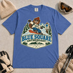 Mystic Blue tee featuring a cheerful bear snowboarding past a blue-square trail sign above the phrase “Blue Square Enthusiast” with “Groomers. Good Vibes. More Runs.”