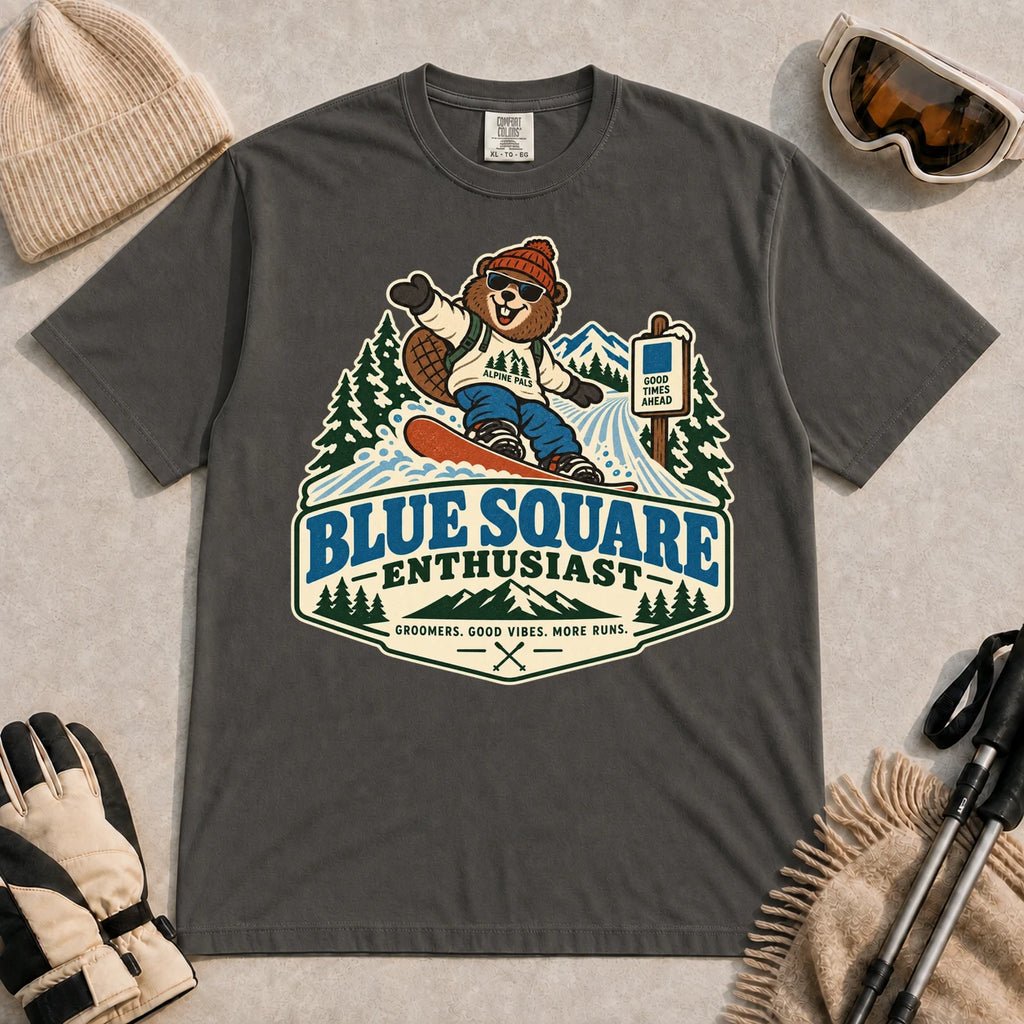 Pepper tee featuring a cheerful bear snowboarding past a blue-square trail sign above the phrase “Blue Square Enthusiast” with “Groomers. Good Vibes. More Runs.”