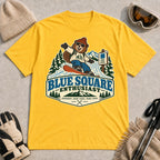 Daisy tee featuring a cheerful bear snowboarding past a blue-square trail sign above the phrase “Blue Square Enthusiast” with “Groomers. Good Vibes. More Runs.”