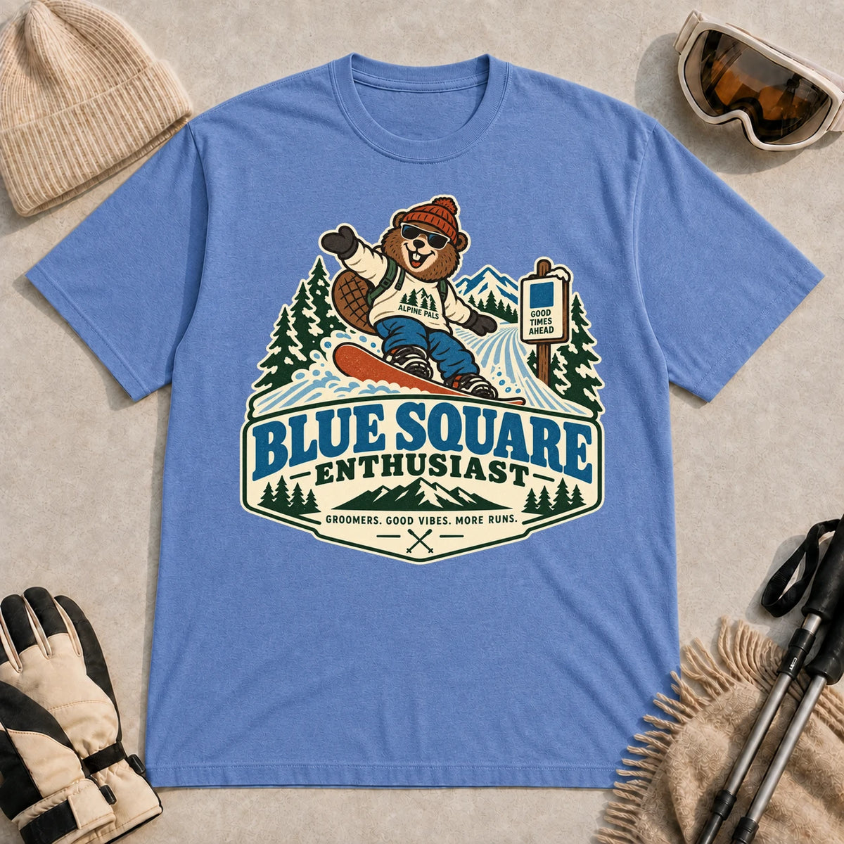 Heather Royal tee featuring a cheerful bear snowboarding past a blue-square trail sign above the phrase “Blue Square Enthusiast” with “Groomers. Good Vibes. More Runs.”