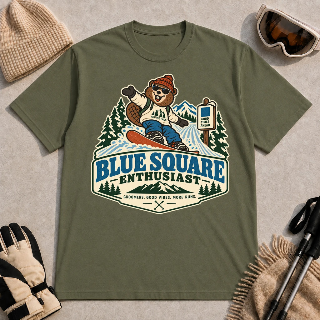 Military Green tee featuring a cheerful bear snowboarding past a blue-square trail sign above the phrase “Blue Square Enthusiast” with “Groomers. Good Vibes. More Runs.”