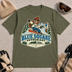 Military Green tee featuring a cheerful bear snowboarding past a blue-square trail sign above the phrase “Blue Square Enthusiast” with “Groomers. Good Vibes. More Runs.”