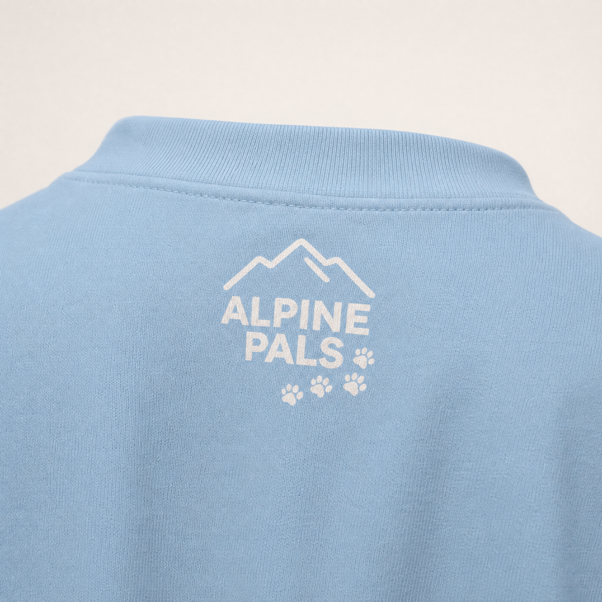 Light blue shirt with 'Alpine Pals' logo on a beige background