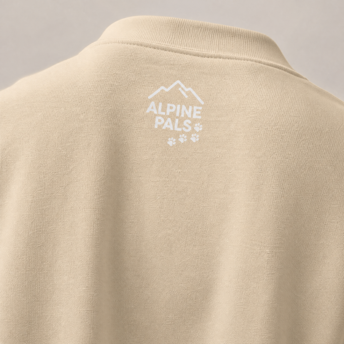 Sand colored sweater with 'Alpine Pals' logo on a gray background