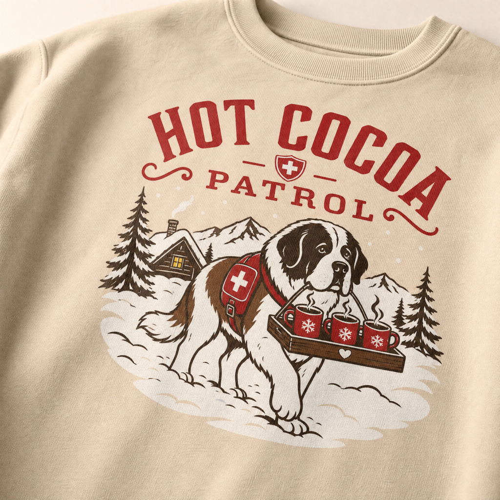 Sand colored sweatshirt with a graphic of a dog carrying hot cocoa mugs and 'Hot Cocoa Patrol' text.