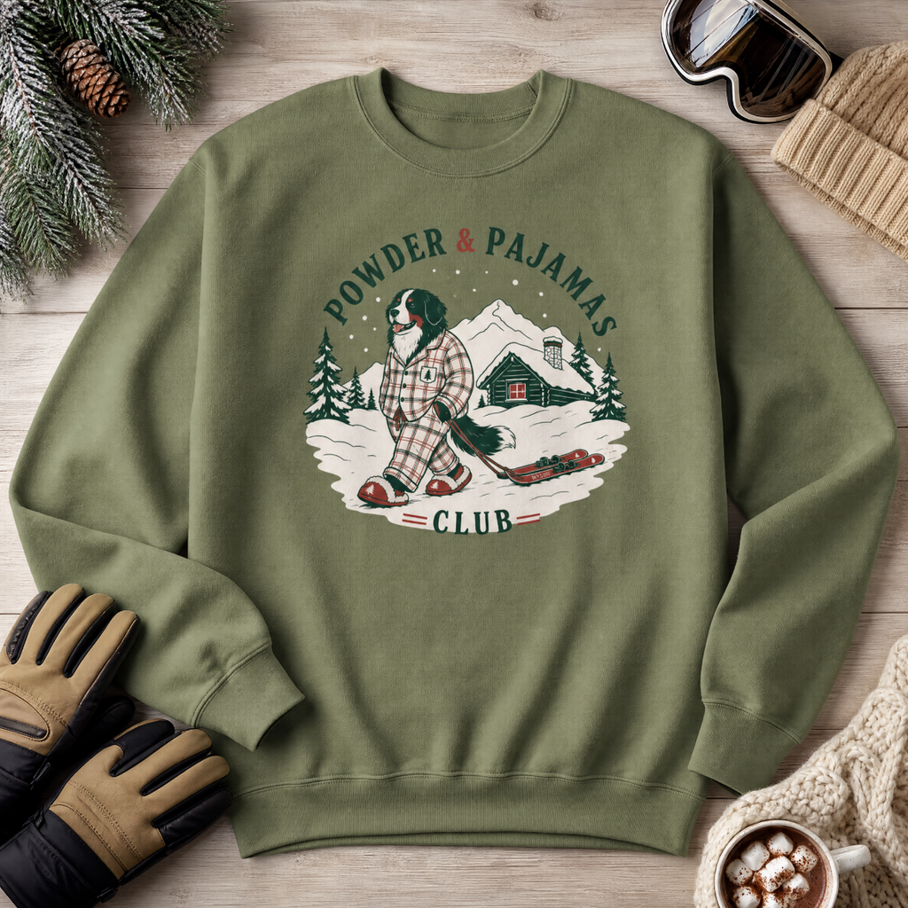 Military green sweatshirt with a winter graphic and text on a wooden surface with winter accessories.