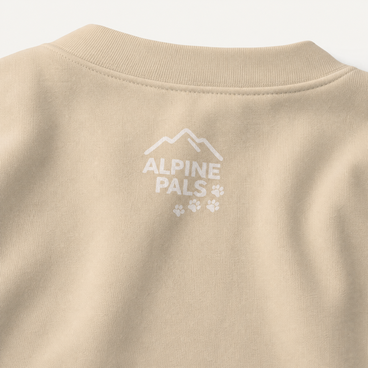 Sand colored sweater with 'Alpine Pals' logo in white on a light gray background