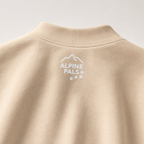 Sand colored sweatshirt with 'Alpine Pals' logo on a light gray background