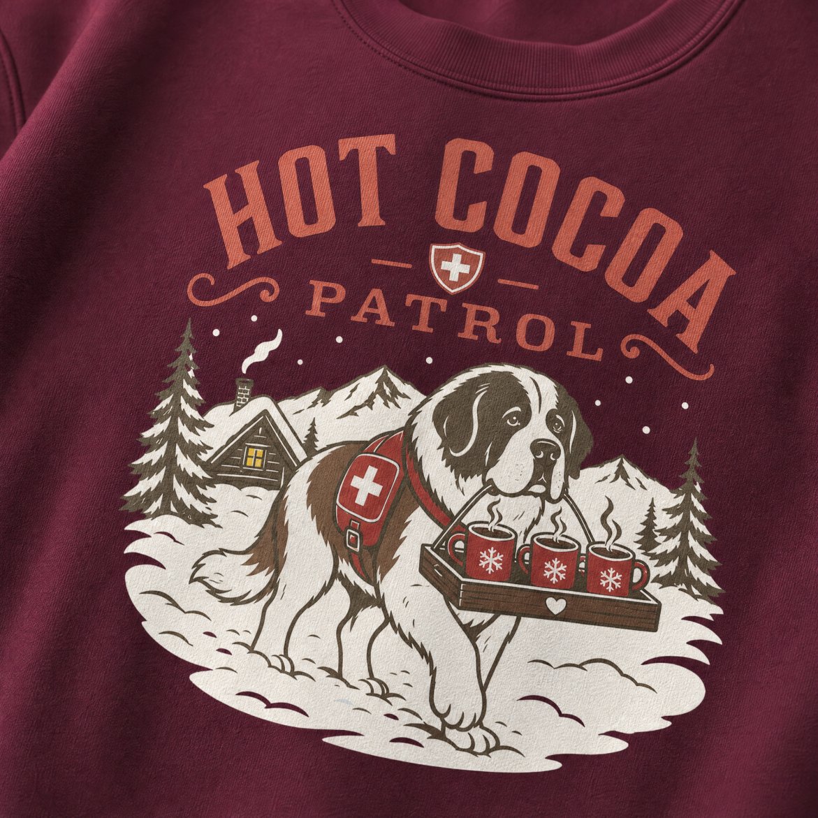 Maroon sweatshirt with a graphic of a dog carrying hot cocoa mugs and 'Hot Cocoa Patrol' text.