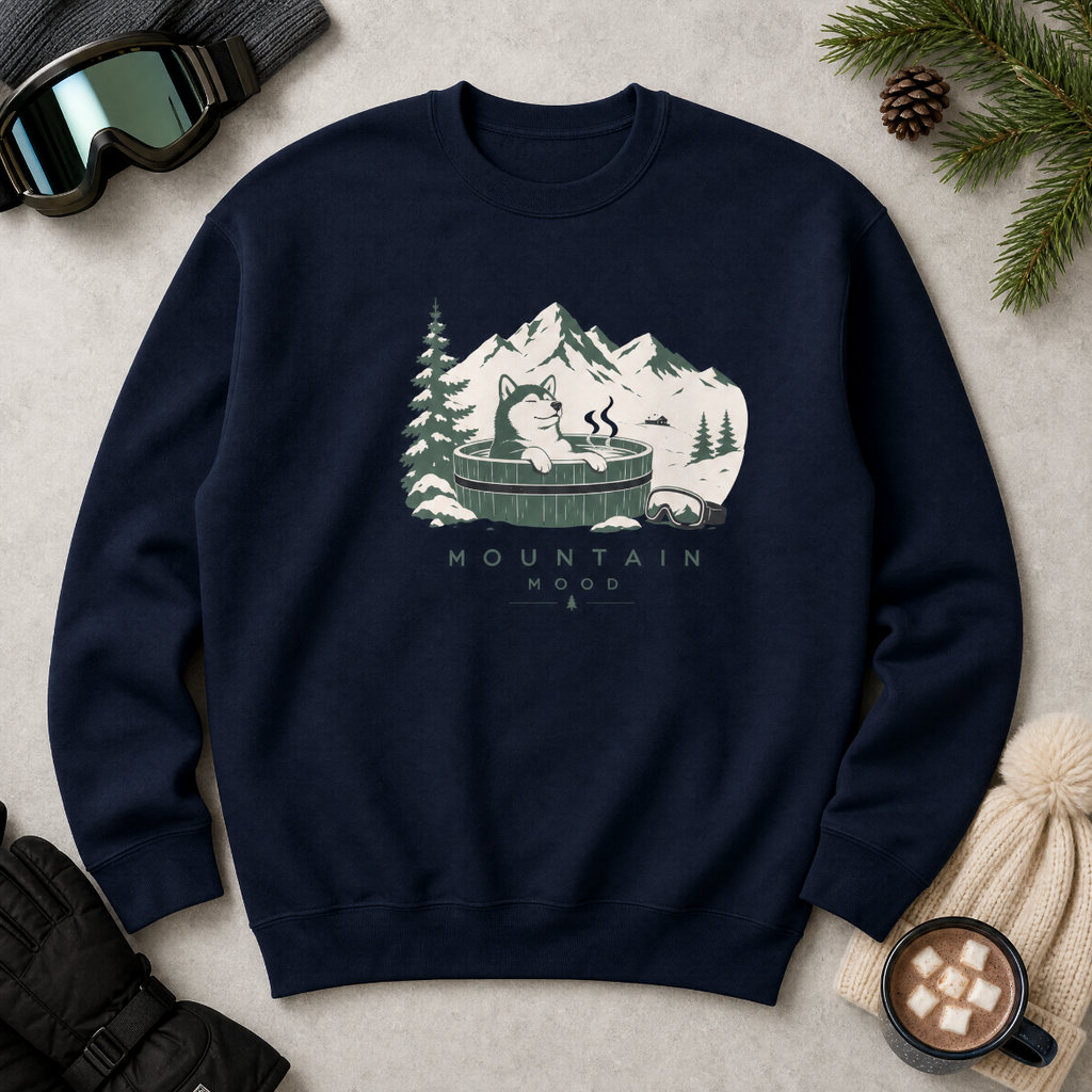 Navy blue sweatshirt with mountain graphic and text on a light surface with winter accessories.