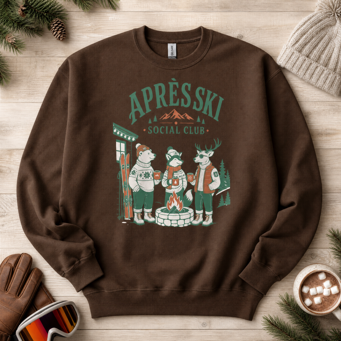 Dark chocolate brown sweatshirt with 'Apres Ski Social Club' graphic on a wooden surface with winter accessories.