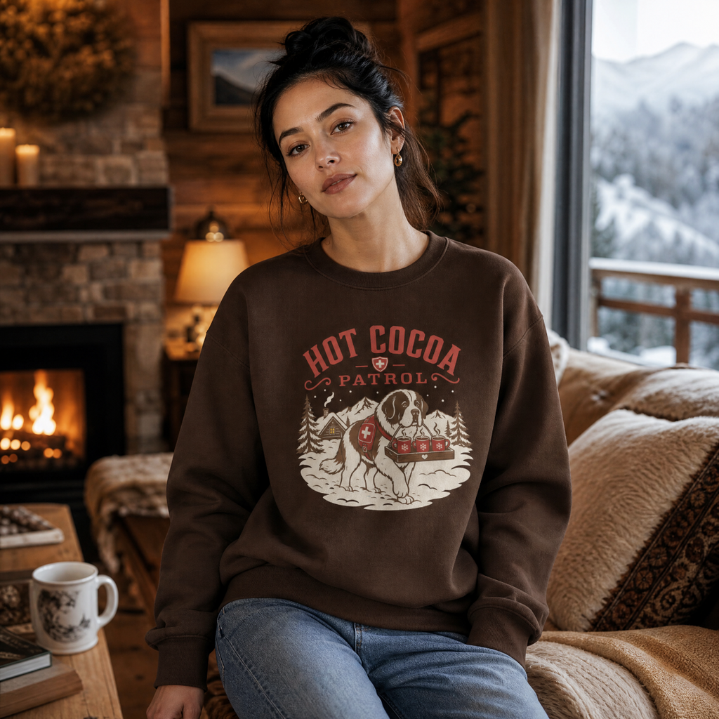 Woman wearing a 'Hot Cocoa Patrol' sweatshirt in a cozy living room with a fireplace and mountain view.