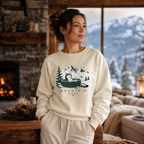Woman wearing a sand colored sweatshirt with a nature graphic in a cozy living room with a fireplace and mountain view.