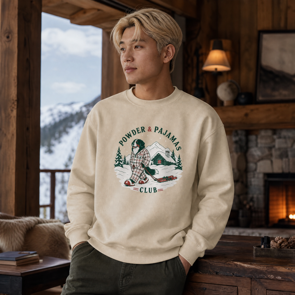 Person wearing a sand colored sweatshirt with a graphic design in a cozy cabin setting