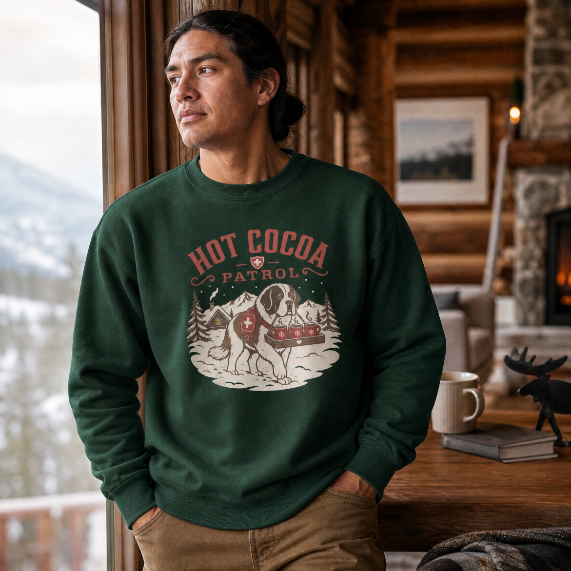 Man wearing a green sweatshirt with 'Hot Cocoa Patrol' design in a cozy cabin setting.