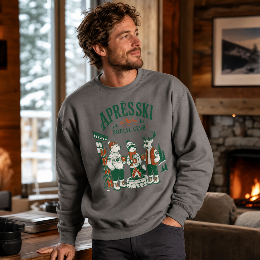 Man wearing a charcoal gray sweatshirt with a winter-themed graphic in a cozy indoor setting.