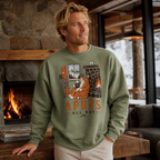 Man wearing a military green sweatshirt with a graphic design and text, standing in a cozy indoor setting with a fireplace.