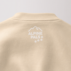 Sand colored sweater with 'Alpine Pals' logo on a light gray background