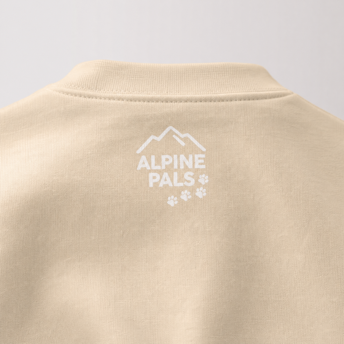 Sand colored sweater with 'Alpine Pals' logo on a light gray background