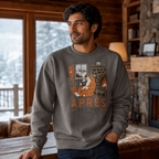 Man wearing a charcoal gray sweatshirt with a fox graphic and 'Apres All Day' text in a cozy room.
