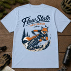 Light Blue tee featuring a sunglasses-wearing fox carving a mountain bike berm, with the phrase “Flow State Activated.”