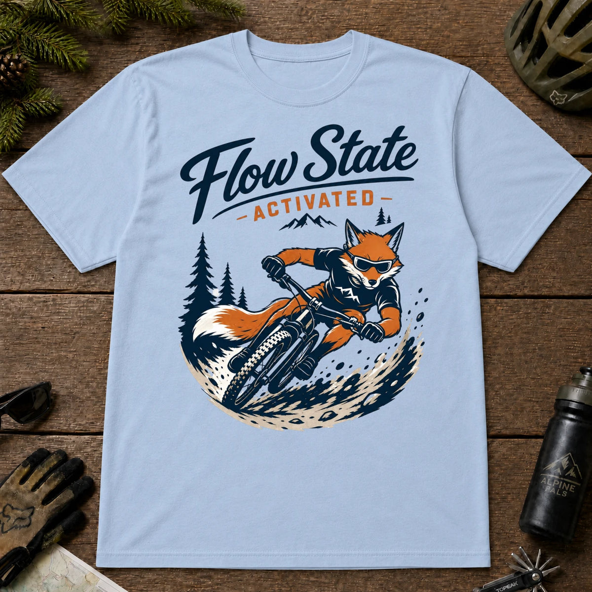 Light Blue tee featuring a sunglasses-wearing fox carving a mountain bike berm, with the phrase “Flow State Activated.”