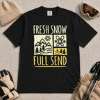 Black tee featuring a retro ski and mountain graphic with the phrase “Fresh Snow, Full Send.”