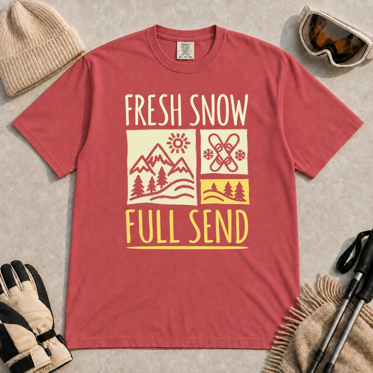 Crimson tee featuring a retro ski and mountain graphic with the phrase “Fresh Snow, Full Send.”