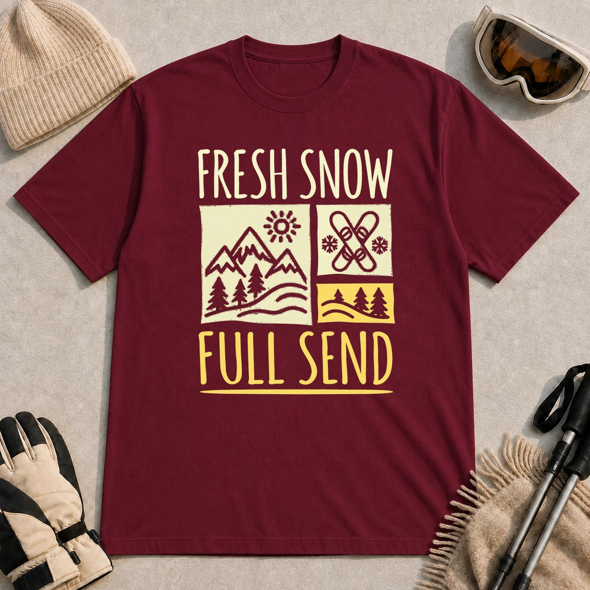 Maroon tee featuring a retro ski and mountain graphic with the phrase “Fresh Snow, Full Send.”