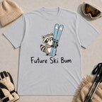 Sport Grey tee featuring a cute raccoon standing beside a pair of skis, with the phrase “Future Ski Bum.”