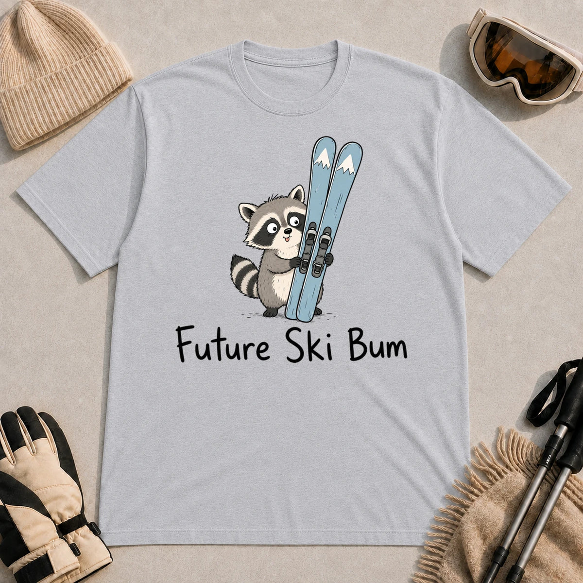 Sport Grey tee featuring a cute raccoon standing beside a pair of skis, with the phrase “Future Ski Bum.”