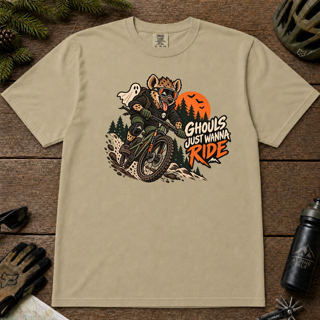 Khaki tee featuring a hyena mountain biking through a spooky Halloween trail scene with a ghost, bats, and orange moon beside the phrase “Ghouls Just Wanna Ride.”