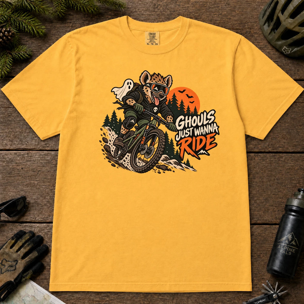 Mustard tee featuring a hyena mountain biking through a spooky Halloween trail scene with a ghost, bats, and orange moon beside the phrase “Ghouls Just Wanna Ride.”
