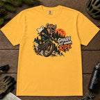 Mustard tee featuring a hyena mountain biking through a spooky Halloween trail scene with a ghost, bats, and orange moon beside the phrase “Ghouls Just Wanna Ride.”