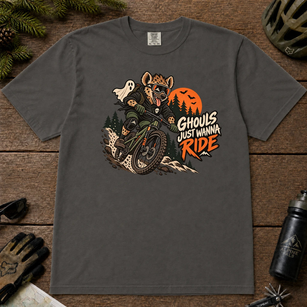 Pepper tee featuring a hyena mountain biking through a spooky Halloween trail scene with a ghost, bats, and orange moon beside the phrase “Ghouls Just Wanna Ride.”