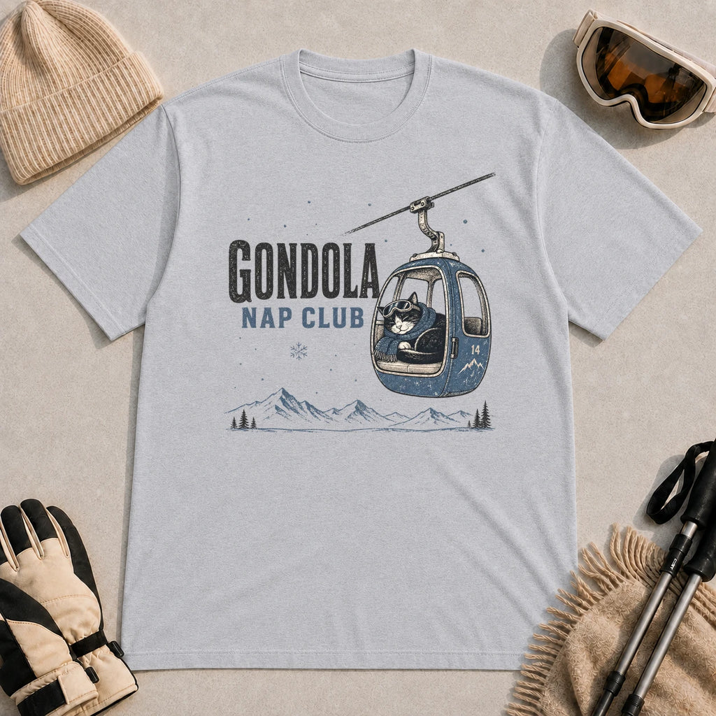 Sport Grey tee featuring a cozy cat napping inside a gondola above a mountain landscape, with the phrase “Gondola Nap Club.”