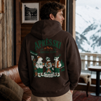 Person wearing a hoodie with 'Après Ski Social Club' design, standing in a cozy room with a snowy outdoor view.