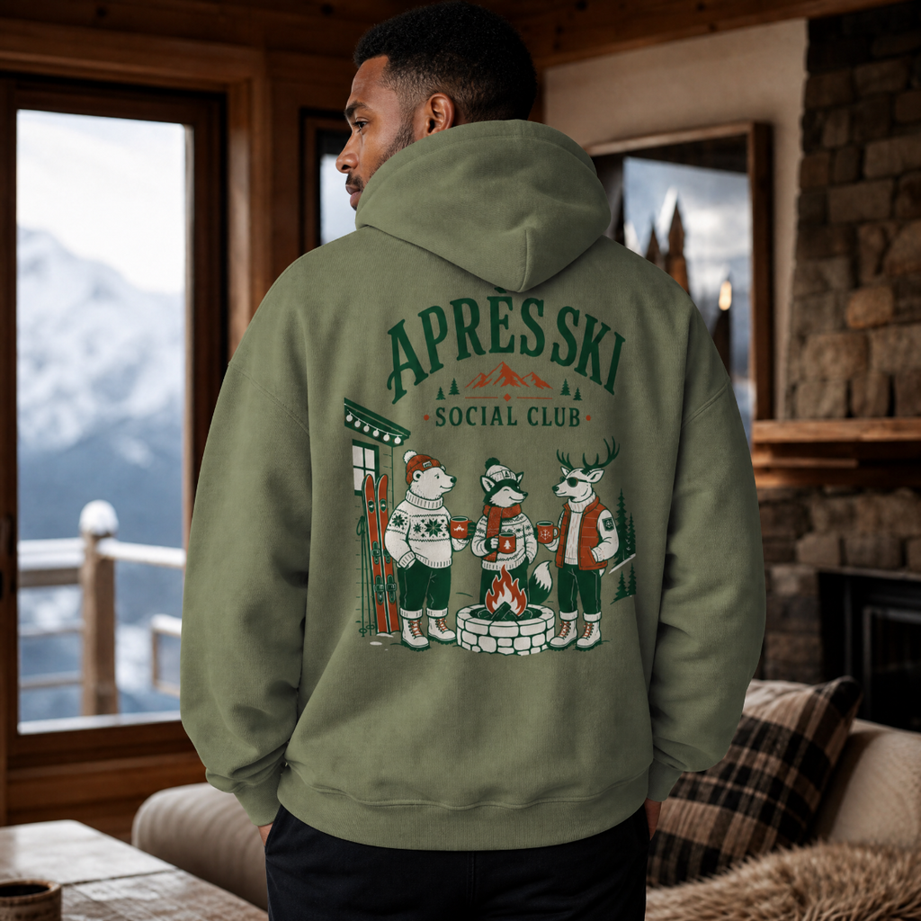 Person wearing a military green hoodie with 'Apres Ski Social Club' design in a cozy room with mountain view.