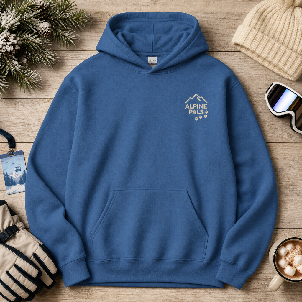 Indigo blue hoodie with 'Alpine Pals' logo on a wooden surface with winter accessories.